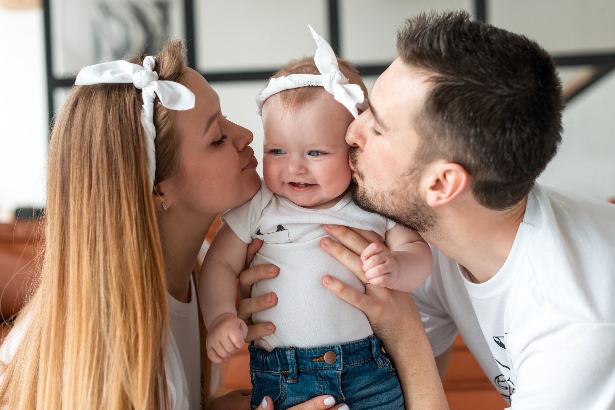 a-mom-and-dad-parent-kissing-their-young-baby.jpg